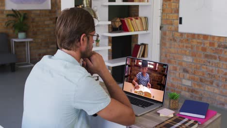 profesor caucásico usando una computadora portátil en una videollamada con una colegiala