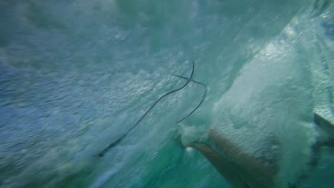 una mujer surfista cayendo de una ola cristalina en la bahía de byron.