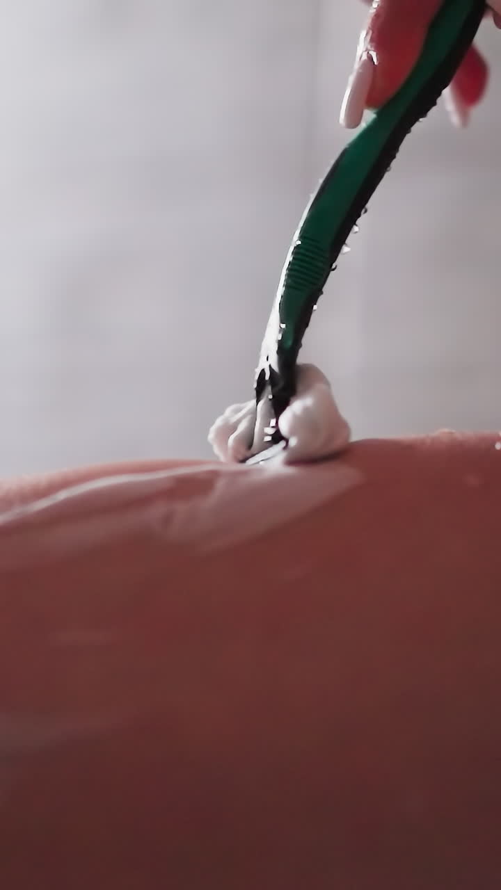 샤워 객실에서 은 다리를 는 여성: 화장실에서 날카로운 도구로 몸의 털을 제거하는 우아한 여성: 아름다움의 일상적인 절차