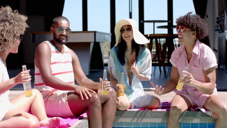diverse friends hanging out, drinking beverages, and enjoying poolside conversation together