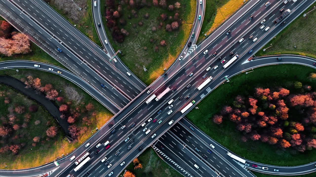 Belebter Autobahnknotenpunkt im Herbst mit bunten Bäumen, Luftaufnahme