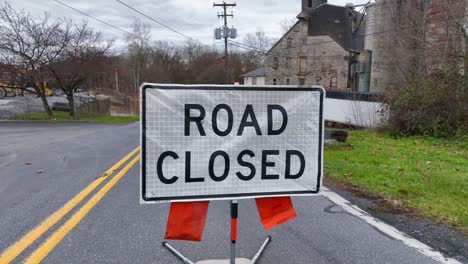 Road-closed-sign-in-front-of-brown-murky-water-flooded-on-street