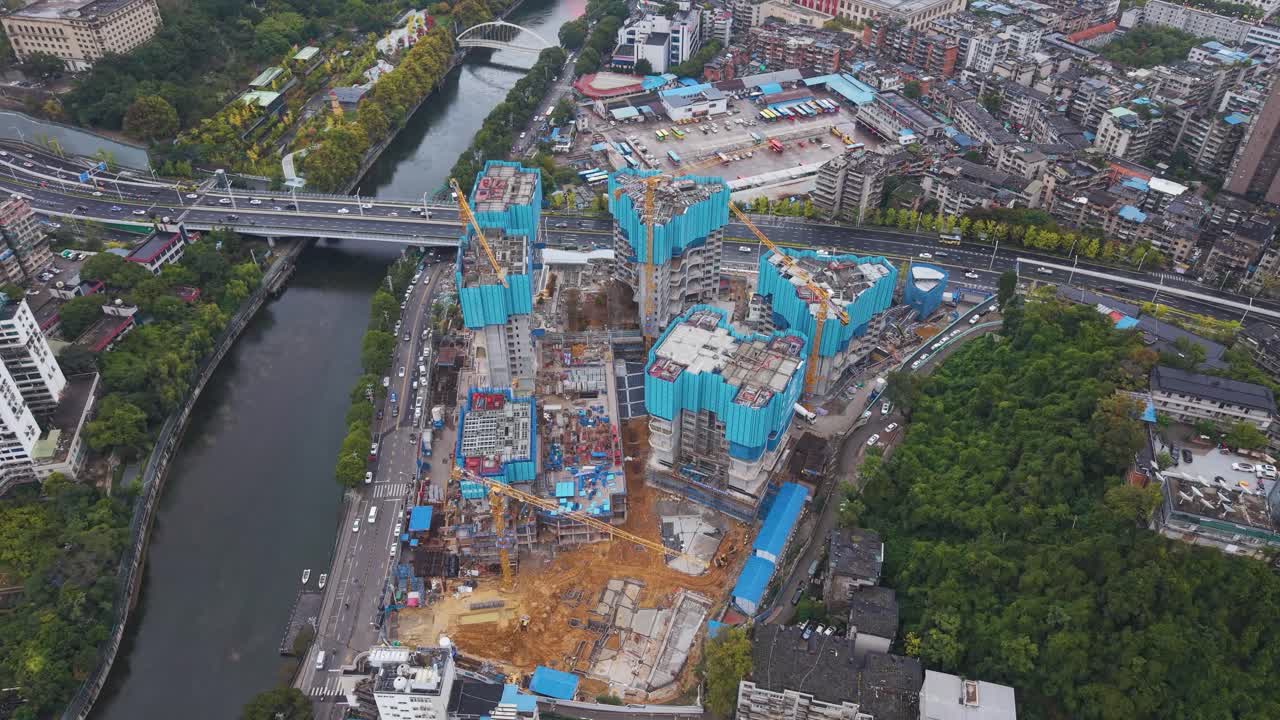 Orbiting drone shot of a high-density construction site in Guiyang, Guizhou Province, China. Highlights multiple cranes, foundation work, and surrounding urban infrastructure