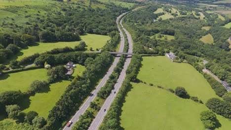 Aerial-establishment-shot-of-the-A30-road-cutting-through-rural-Devon,-UK