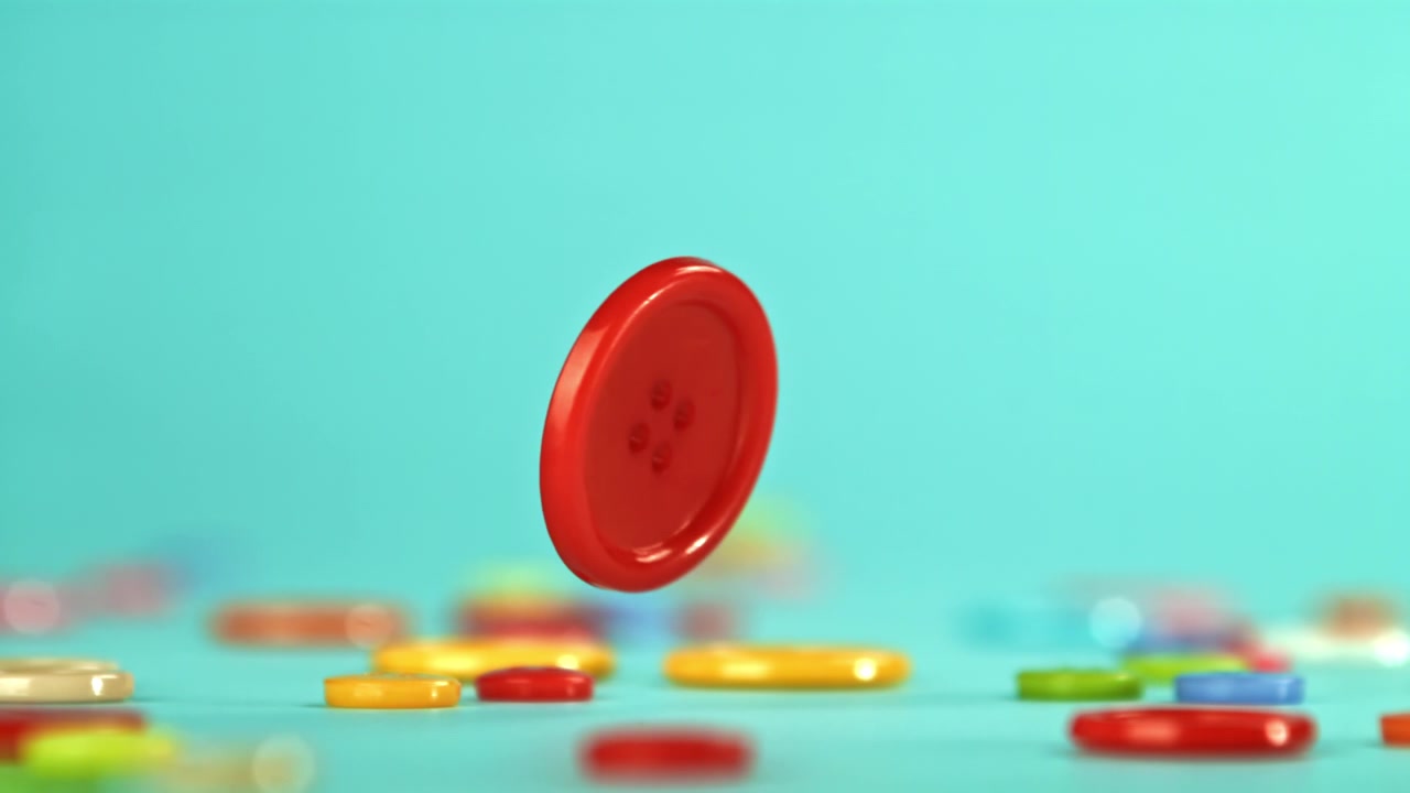 Botão Vermelho Caindo e Quicando em Câmera Lenta em um Fundo Azul.