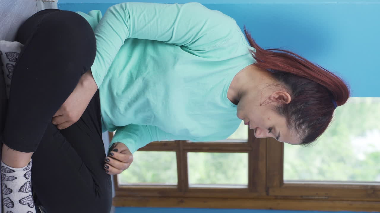 벽  ⁇ 에 앉아 있는 여자의 수직 비디오는 그녀의 빈 지갑을 보고 있습니다. 깨졌습니다.