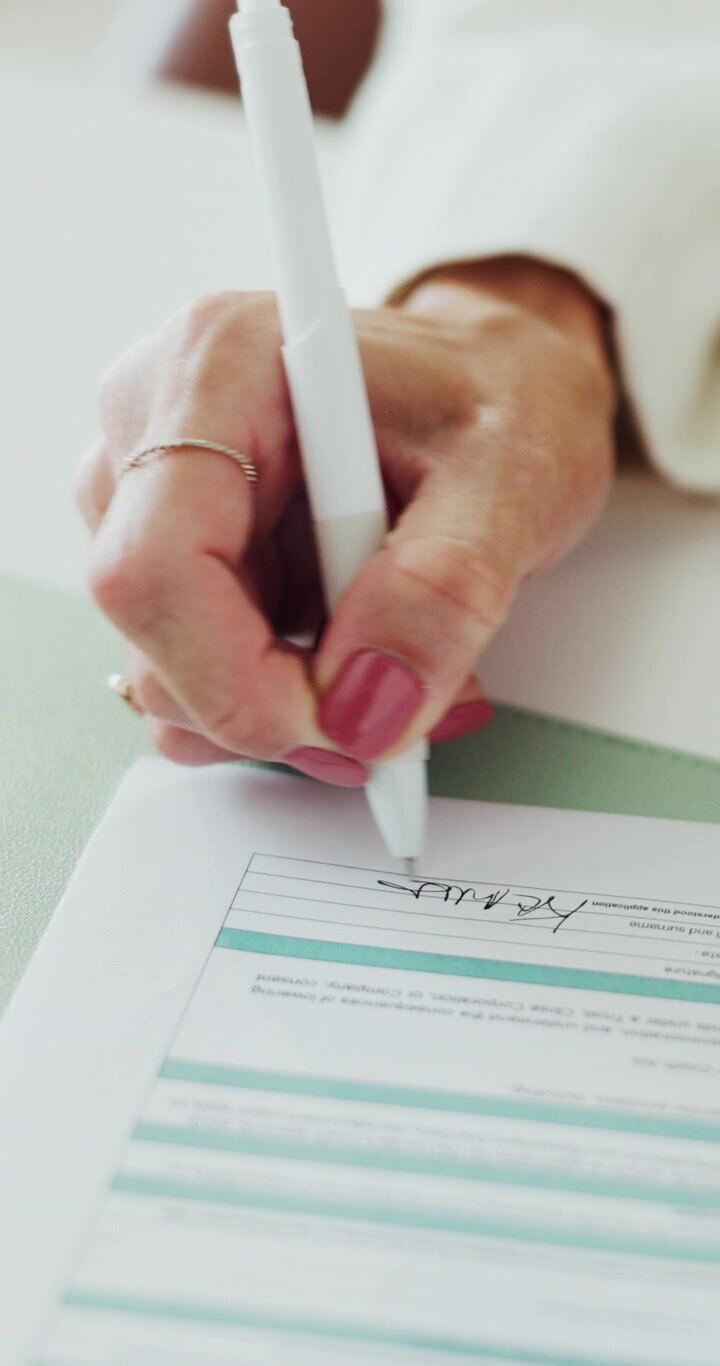 Woman Signing a Legal Document with a White Pen