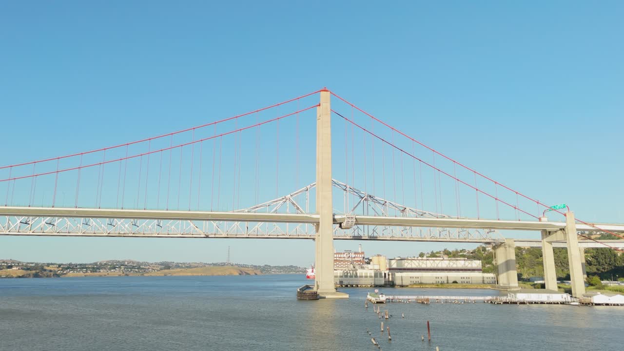 Aerial push in of Crockett’s waterfront that leads into the detailed geometry of the Alfred Zampa Bridge, bathed in crisp afternoon light