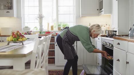 Happy-senior-caucasian-woman-standing-in-kitchen-and-preparing-dinner