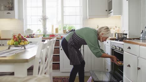 gelukkige senior blanke vrouw die in de keuken staat en het diner voorbereidt