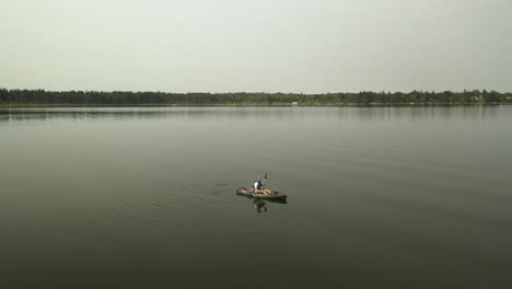 Aerial-parallax-around-kayaker-on-lake-in-Boreal-Forest,-Saskatchewan,-Canada
