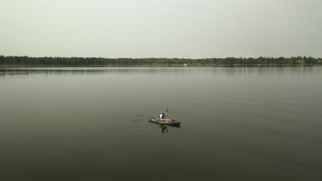 aerial parallax around kayaker on lake in boreal forest, saskatchewan, canada