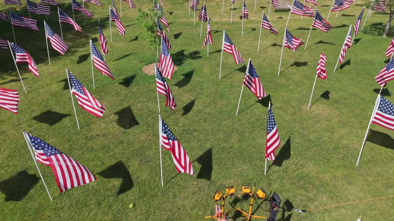 American Flags On Field With Green Grass In Massachusetts, United States. drone pullback shot