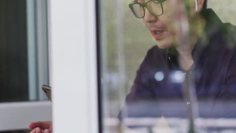 asian man wearing wireless earphones having a video call on digital tablet while sitting at a cafe