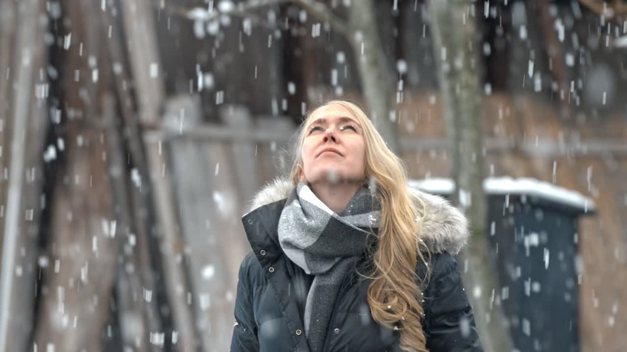 A woman stands in the serene beauty of Shirakawa-go, Japan, embracing the snowfall around her.