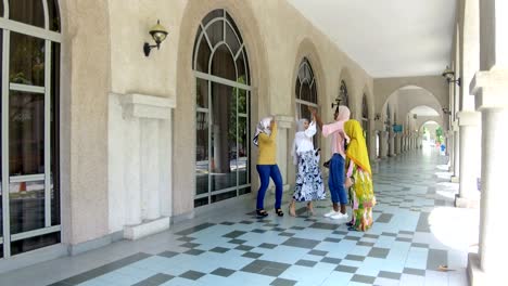 female students in hijab celebrating success with high-five and selfie