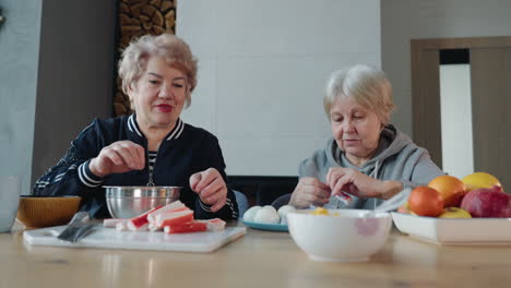 two senior women preparing a meal together