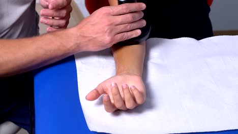 fisioterapeuta tratando el brazo de un paciente con un rayo láser
