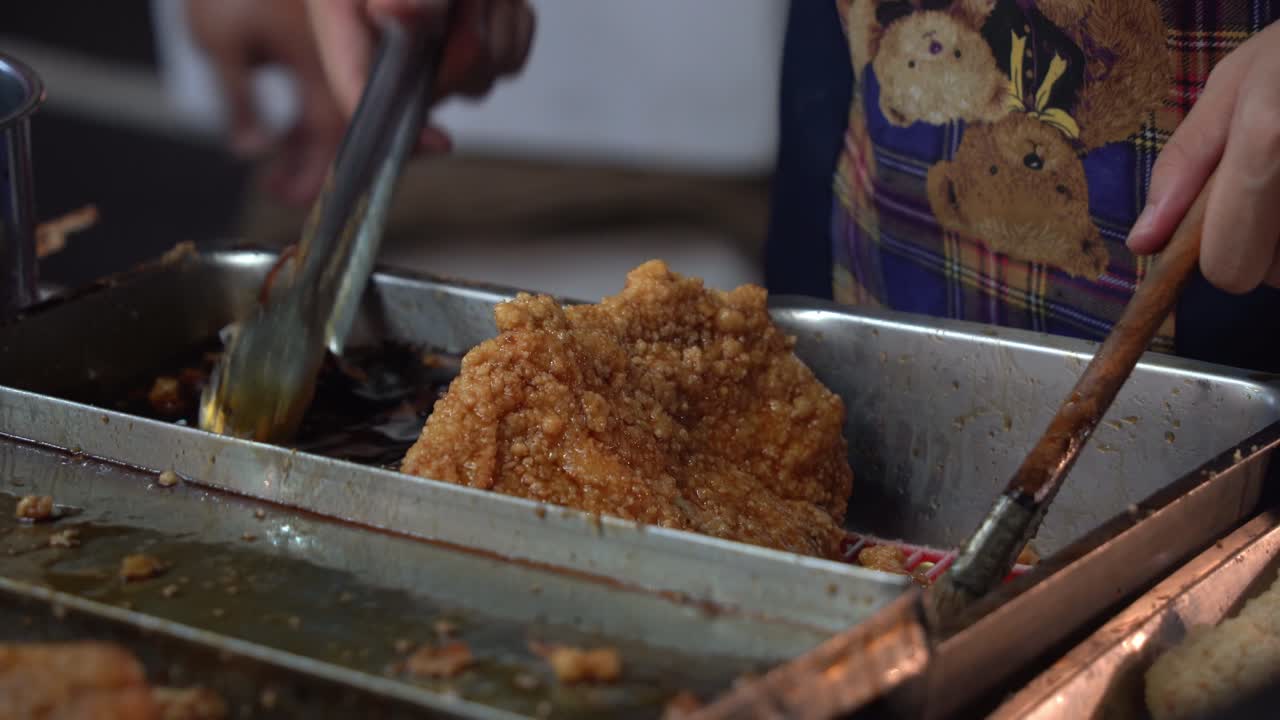 맛있고 맛있는 꿀 코팅된 프라이드 치킨 요리가 진행 중이며, 바삭한 치킨 필레를 간장 꿀 소스에 담그는 요리사는 아시아 대만의 유명한 야시장에서 그릴 준비를 합니다.
