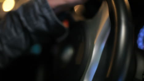 male hands rotating car steering wheel. close up of man driving car at night