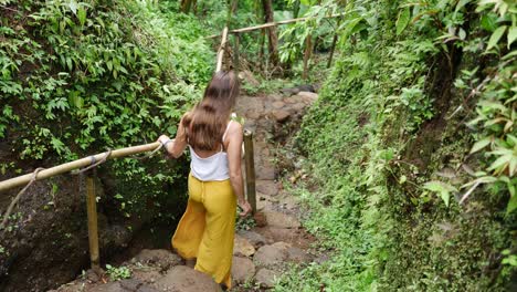 a young, attractive woman in a beautiful and relaxed outfit is walking down steps holding a handrail made out of natural bamboo