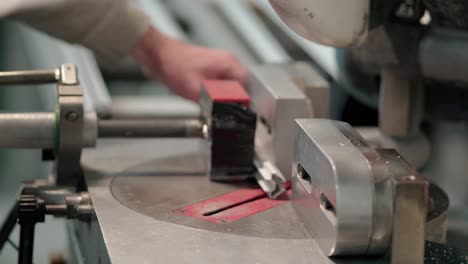 hands of a man cutting aluminum with electric saw inside a window factory