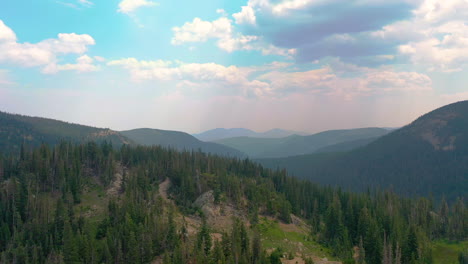 Aerial-Drone-Reveal-of-Nederland-Colorado-Mountain-Views-and-Clouds-Casting-Shadows-Over-Lush-Pine-Tree-Forest-during-Summer-in-the-Rocky-Mountains