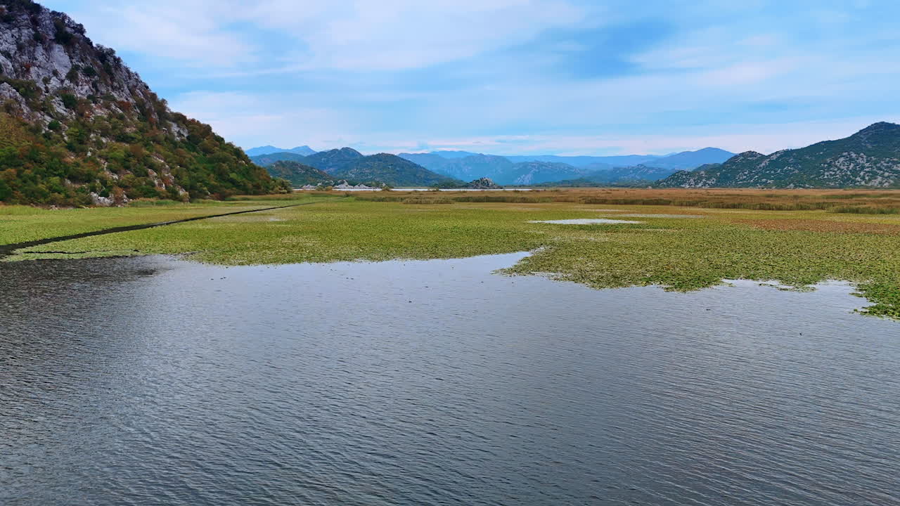 Ulcinj, Montenegro, 14 August 2025: Lake Boats and Wetlands. Multiple boats navigate calm lake wetlands surrounded by green fields