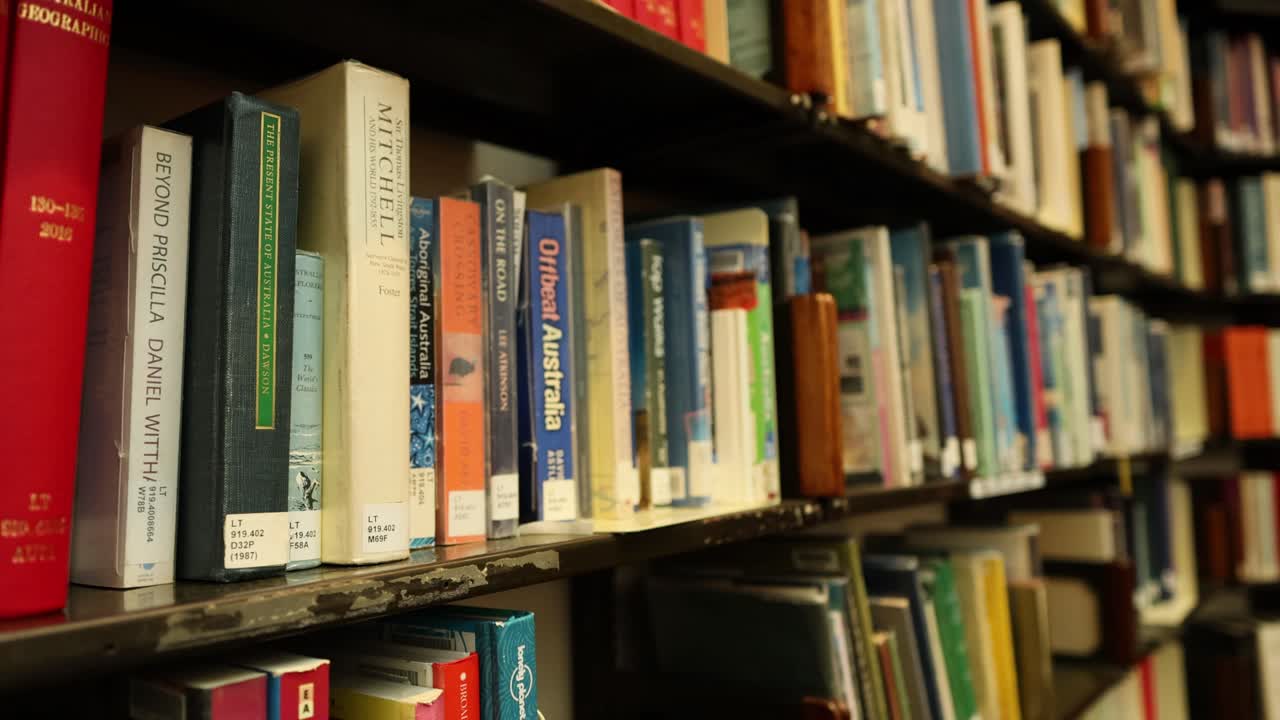 A person selects a book from a library shelf