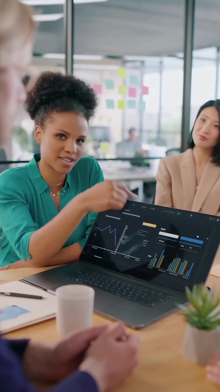 Diverse Business Team Discussing Data and Charts on Laptop in Office