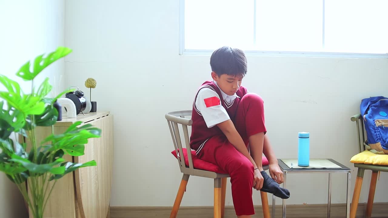 Young asian student diligently wearing socks before school