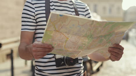 happy male tourist holding a city map and smiling at the camera in the street