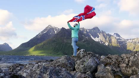 woman with a waving flag of norway on the background of nature