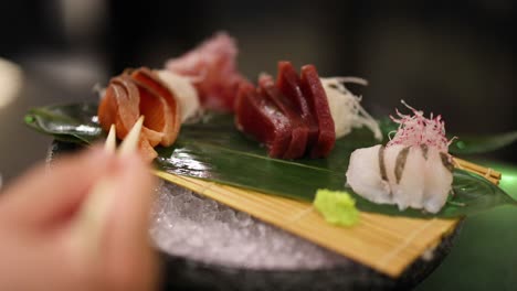 person eating sushi from a bamboo platter