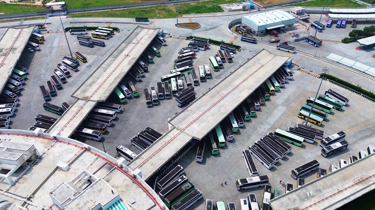 Drone zoom-in shot of dozens of busses at the world's biggest bus terminal, the Kilambakkam Bus Terminus in Chennai, India