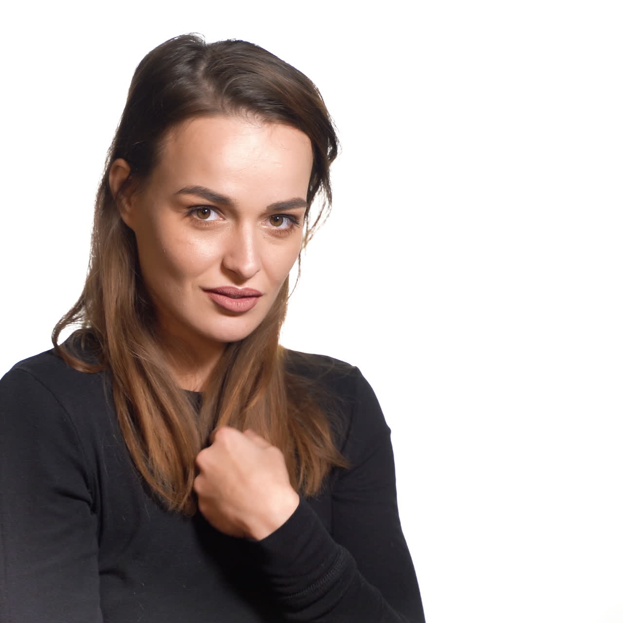 A sexy girl in black golf is posing and tidying one's her hair on a white background in the studio.