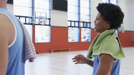 Happy-diverse-male-basketball-team-relaxing-during-training-session-in-indoor-court,-slow-motion