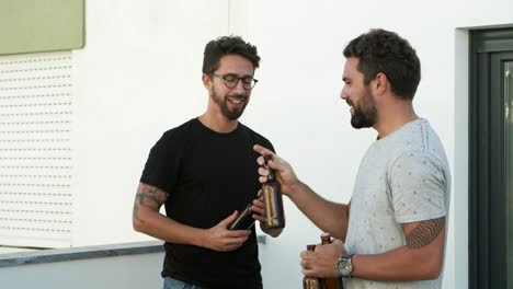 joven sonriente trayendo botellas de cerveza para sus amigos