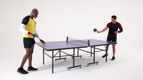 playing table tennis, two men competing in match in studio setting