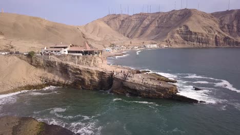 a breathtaking aerial view of rugged coastal cliffs, blue ocean waves, and a unique seaside restaurant. perfect for travel blogs, editorial use, and high-quality prints.