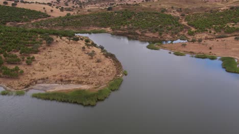 aerial ascending revealing river flowing between riverbanks, alentejo