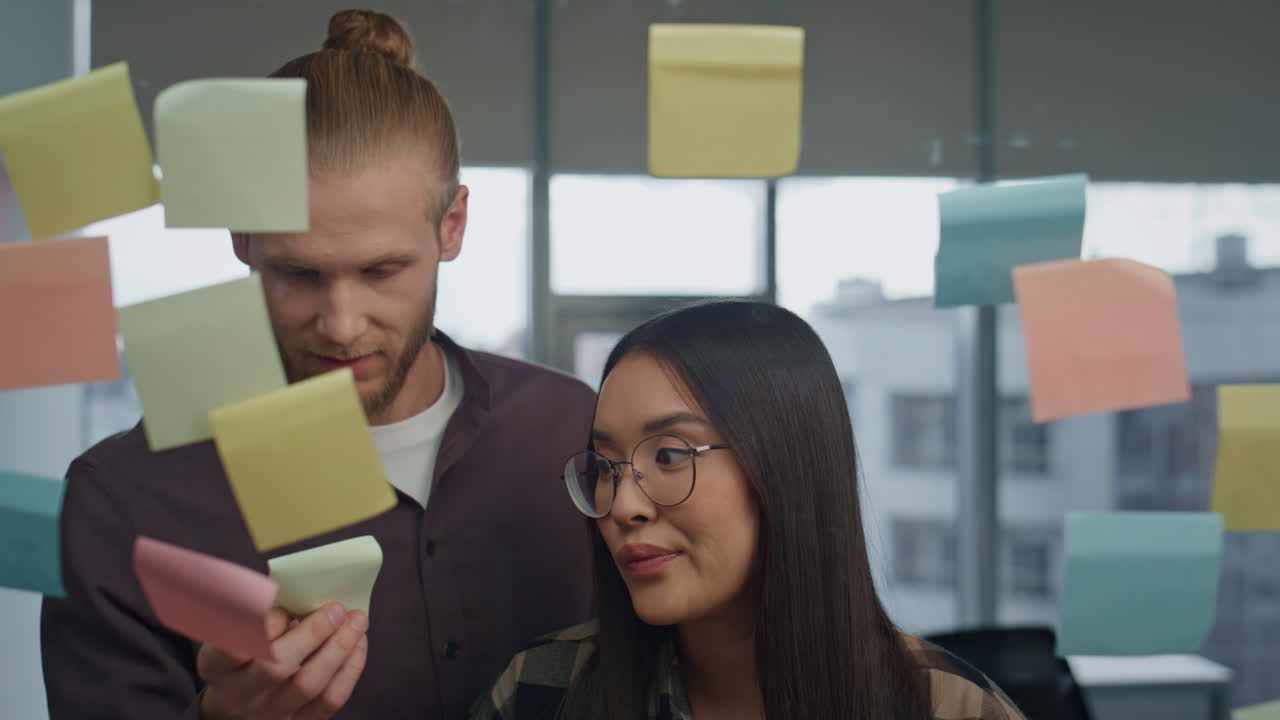 Friendly colleagues discussing glass board office portrait. Couple having fun