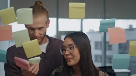 friendly colleagues discussing glass board office portrait. couple having fun