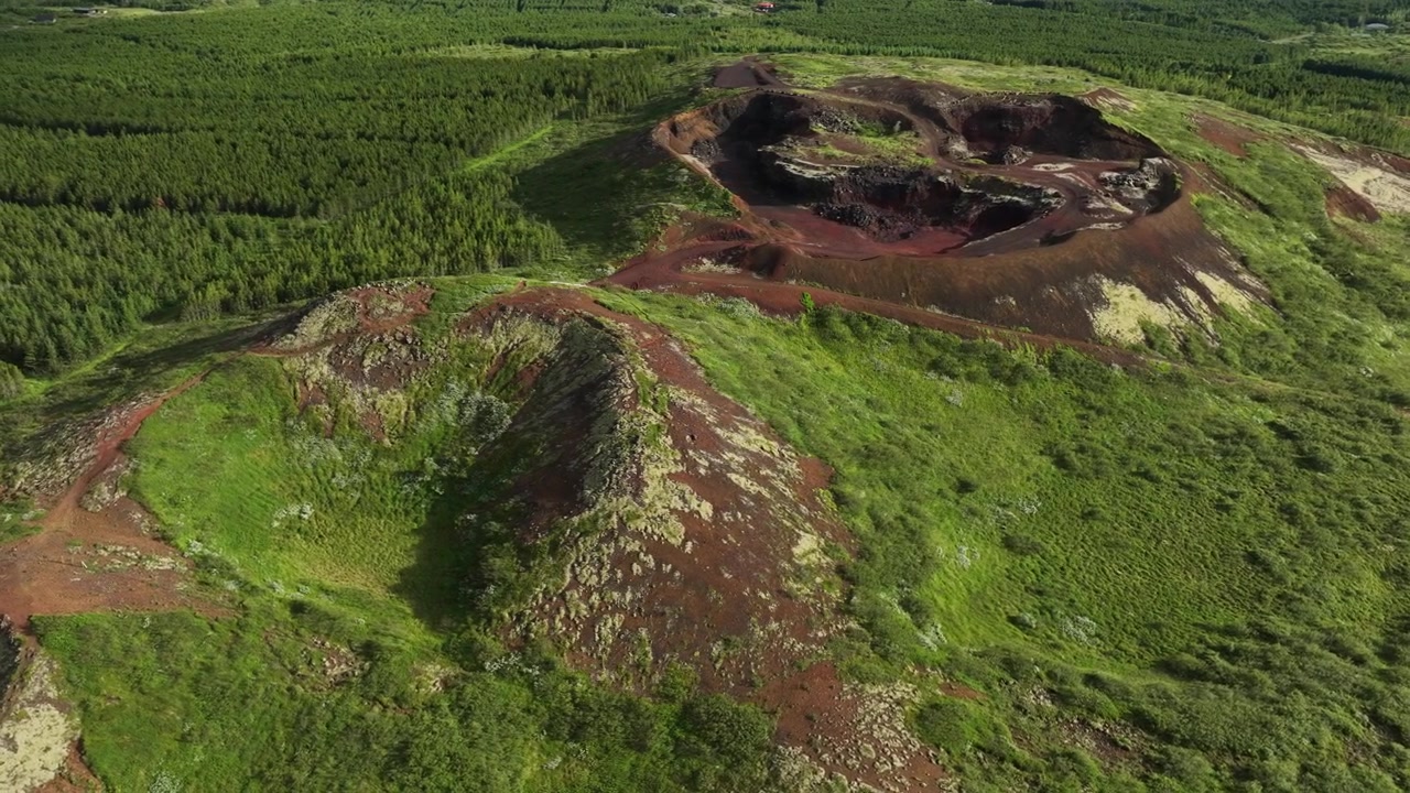 Luchtfoto van het vulkanische terrein rond de Kerid Krater in IJsland, met rode aarde, groene vegetatie en ruige formaties