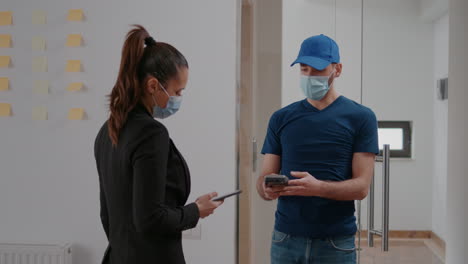 delivery guy with protection face mask holding pos terminal delivering takeaway food order