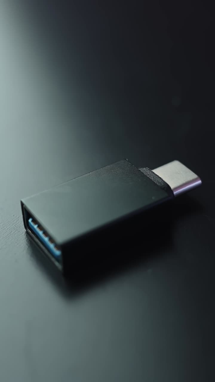 Macro shot of USB-C to USB 3.0 adapter on dark desk with soft bokeh and lots of copy space, modern minimal tech vibe in vertical frame
