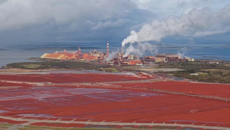 russian-owned aughinish alumina refinery with red sludge waste, smoke, and factory view