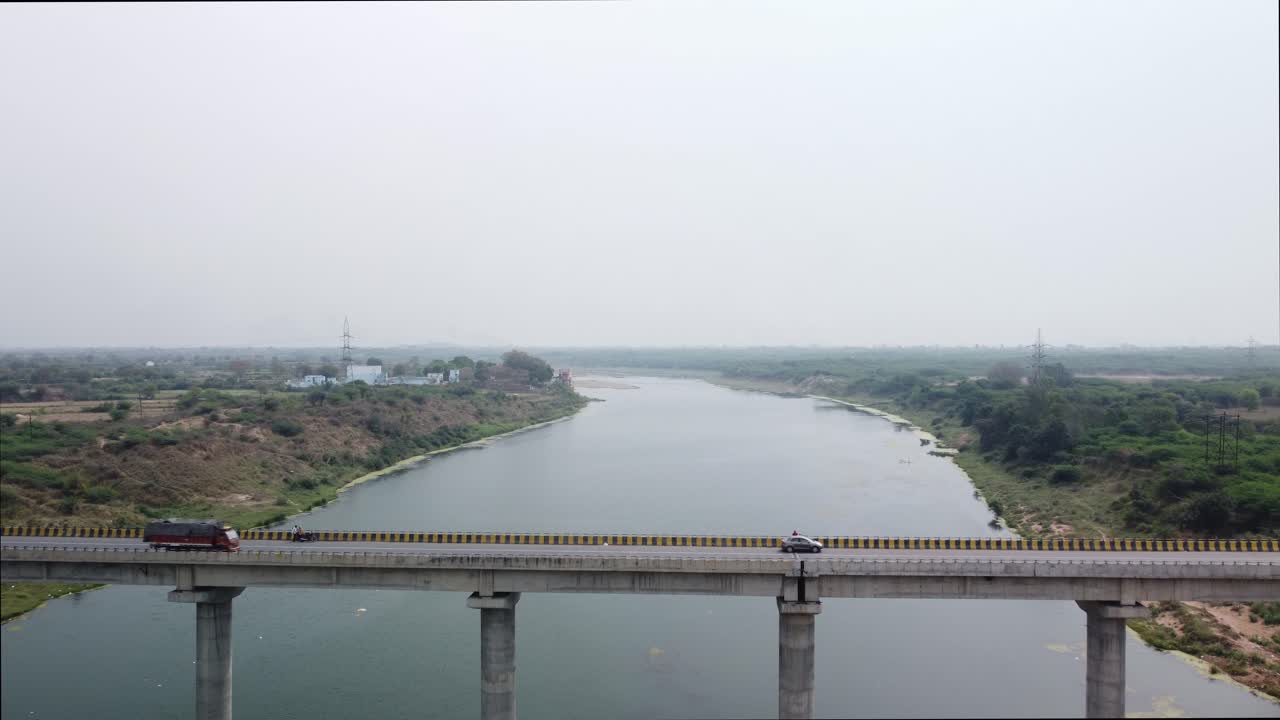 Cinematic aerial view of the highway bridge built over the river basin in the mainland Indian rural terrain, India