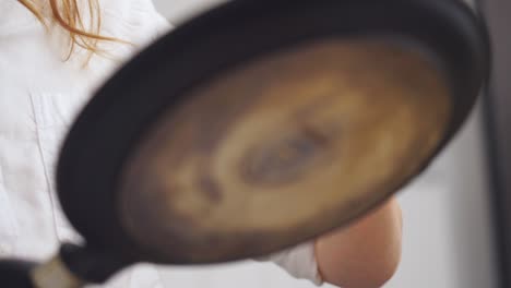 anonymous cook putting the dough for a pancake in the pan