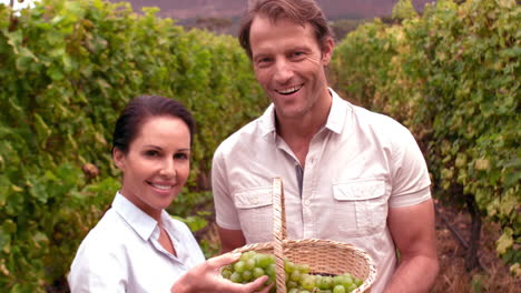 smiling couple holding grapes in slow motion